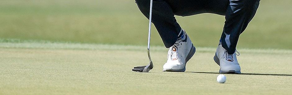 A golf player weighs up a putt on the green during a PGA Tour tournament
